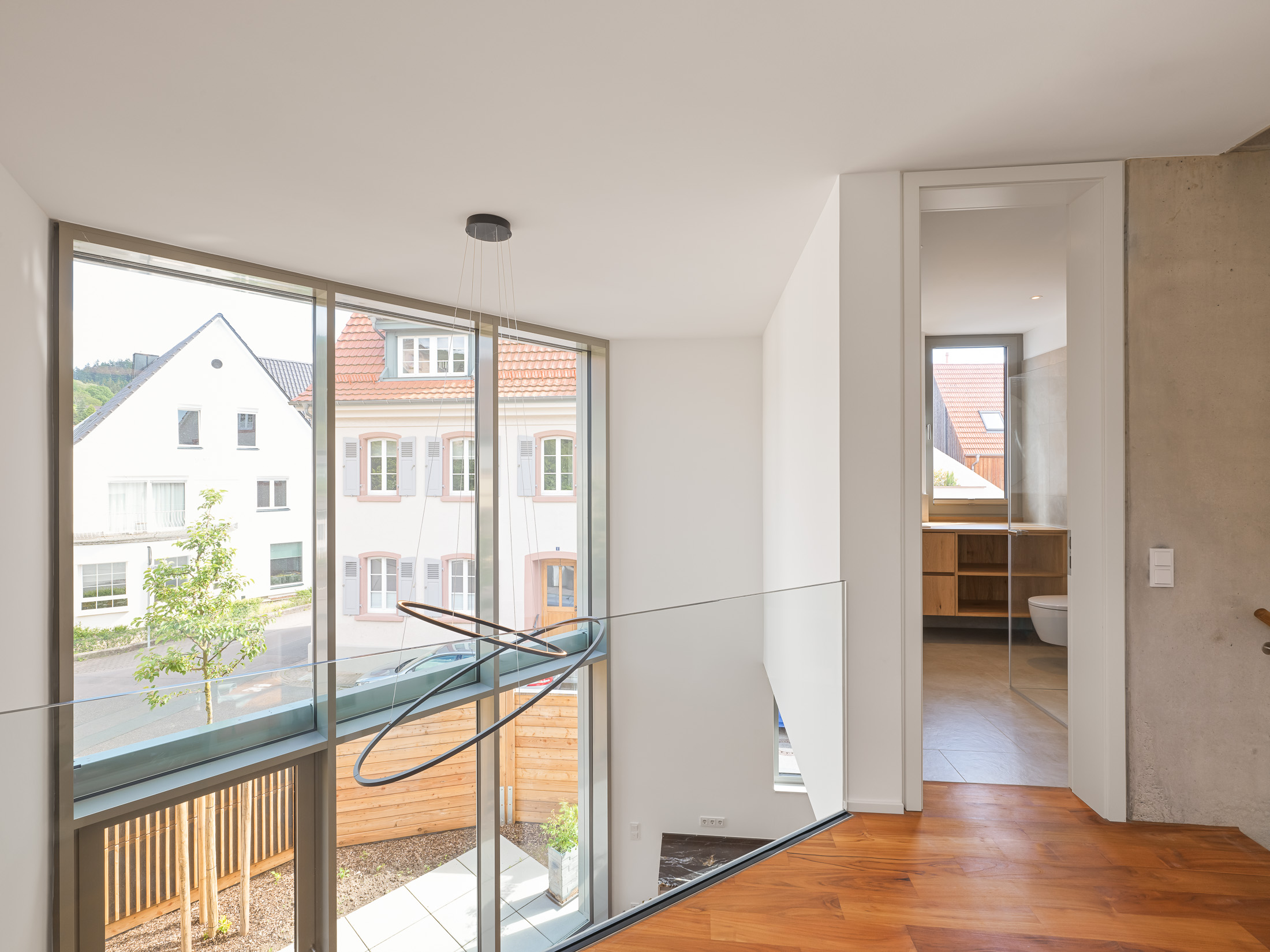 Mehrgeschossiger Luftraum über dem Wohnbereich mit Blick auf die zweigeschossige Pfosten-Riegel-Fassade und die bewaldete Hügellandschaft des Odenwaldes.