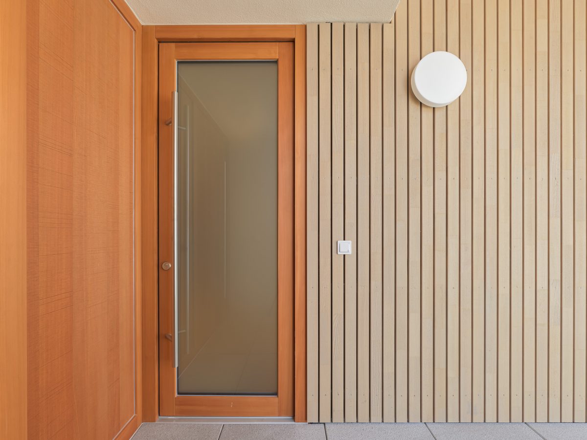 Neubau eines modernen Mehrfamilienhauses -Wohnungseingangstür von Laubengang aus Holz und Glas