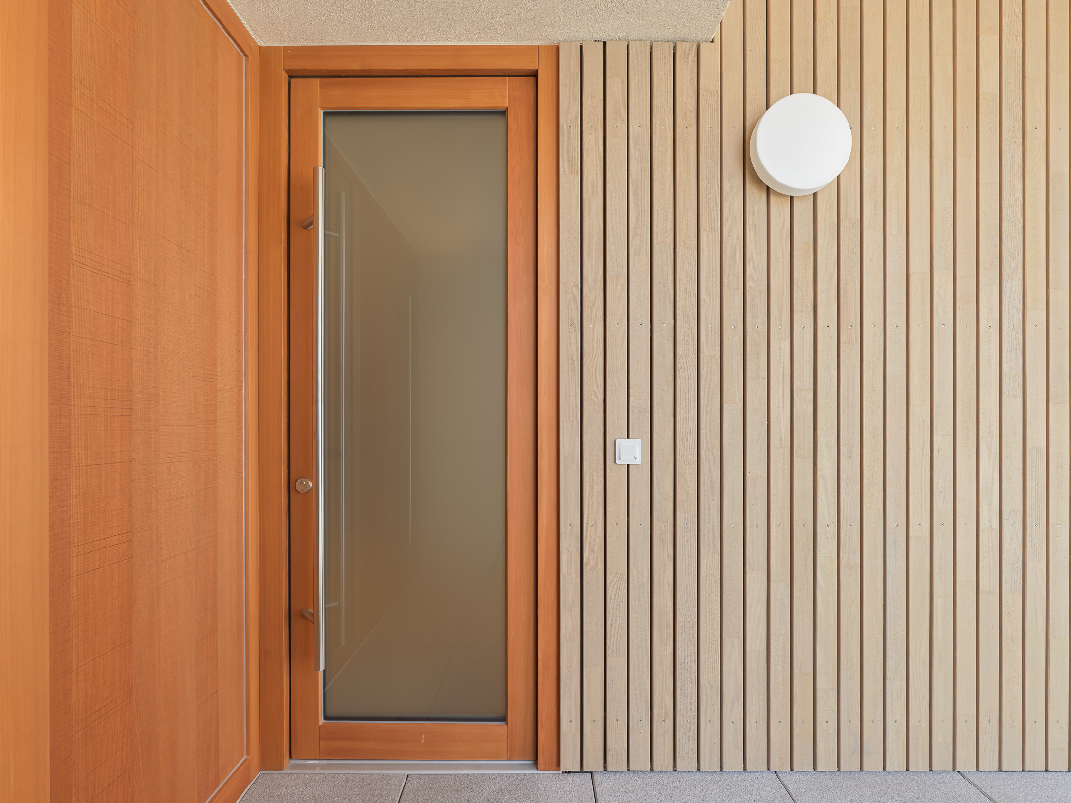 Neubau eines modernen Mehrfamilienhauses -Wohnungseingangstür von Laubengang aus Holz und Glas