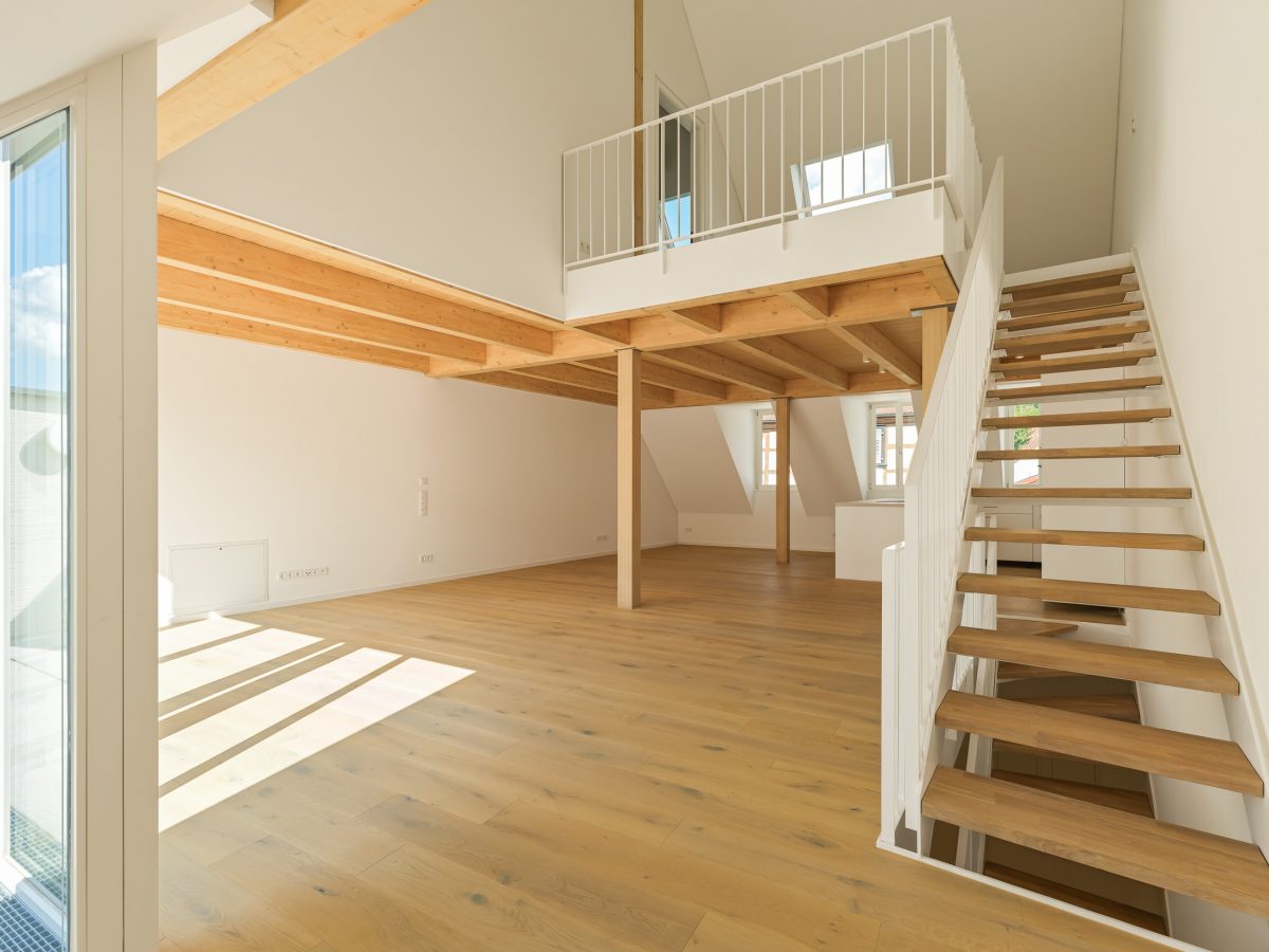 Neubau eines modernen Mehrfamilienhauses - Maisonettewohnung mit Stahlwangentreppe zu offenem Galeriegeschoss unter traditionellem Satteldach