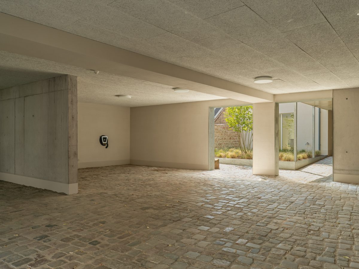 Neubau eines modernen Mehrfamilienhauses mit offener Mehrfachgarage und begrüntem Innenhof