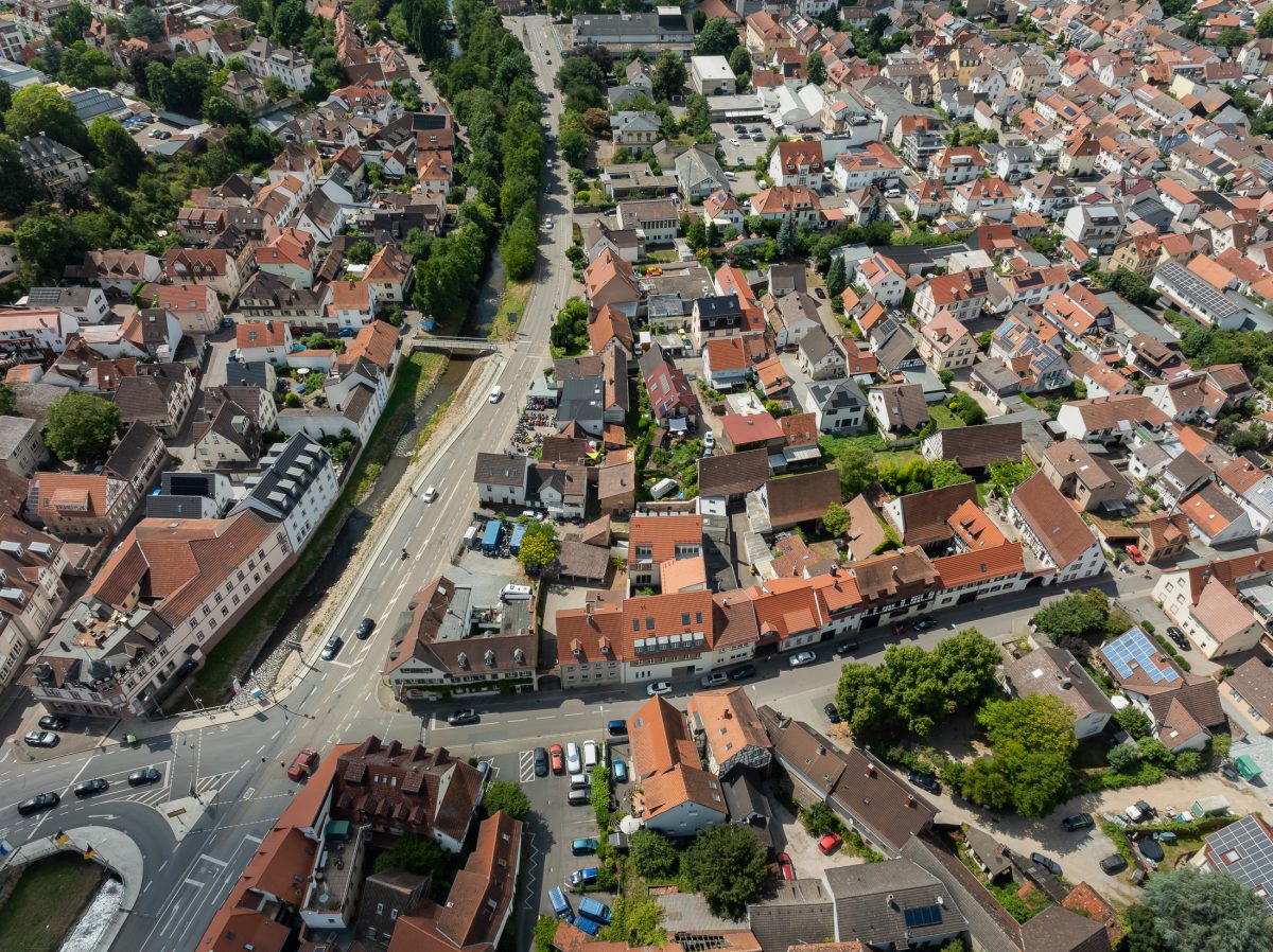 Neubau eines modernen Mehrfamilienhauses mit begrüntem Innenhof im historischen Kontext mit Besenstrichputz, Holzschalung, Schiebeläden und modernen Gauben.