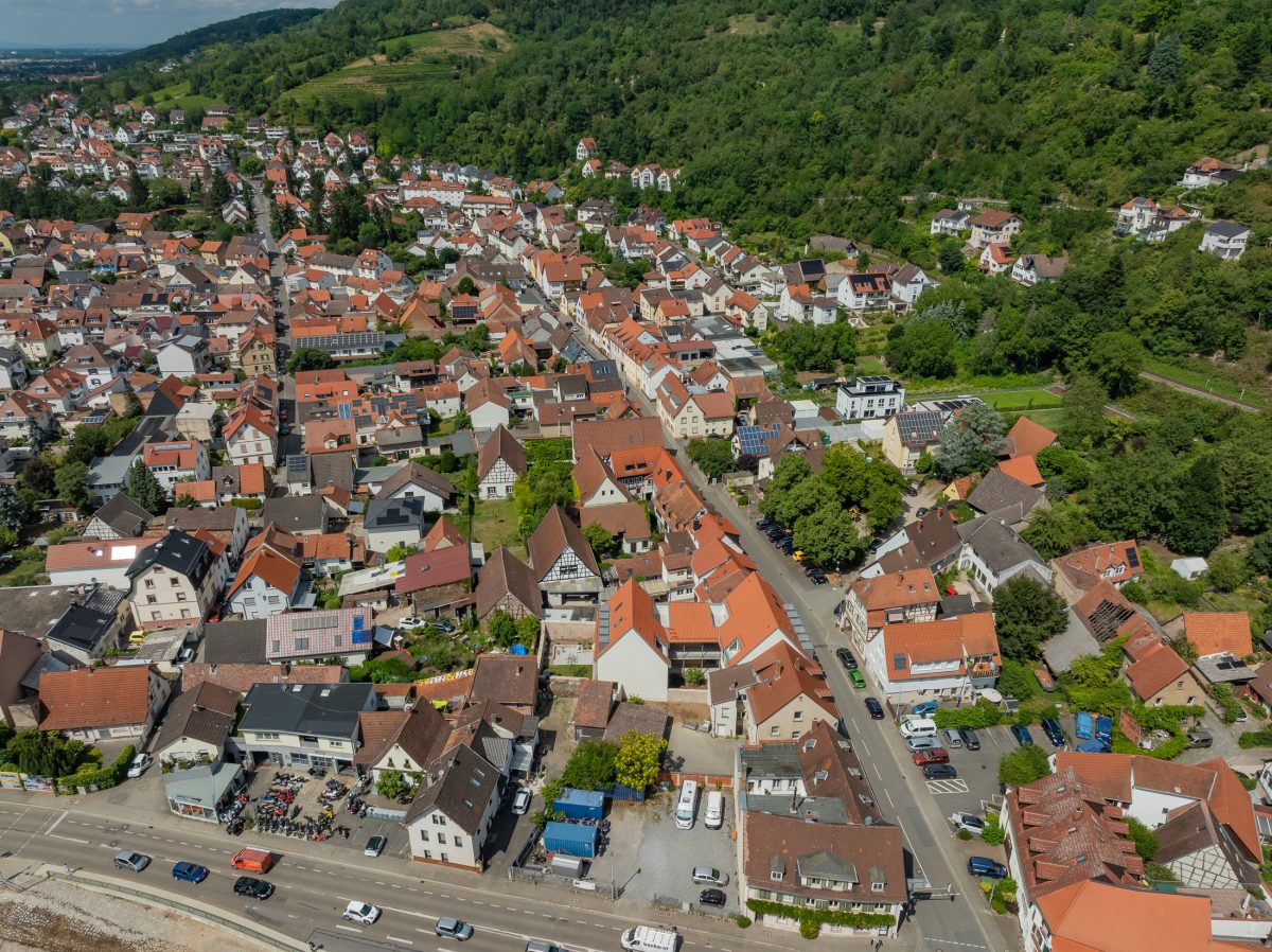 Neubau eines modernen Mehrfamilienhauses mit begrüntem Innenhof im historischen Kontext mit Besenstrichputz, Holzschalung, Schiebeläden und modernen Gauben.