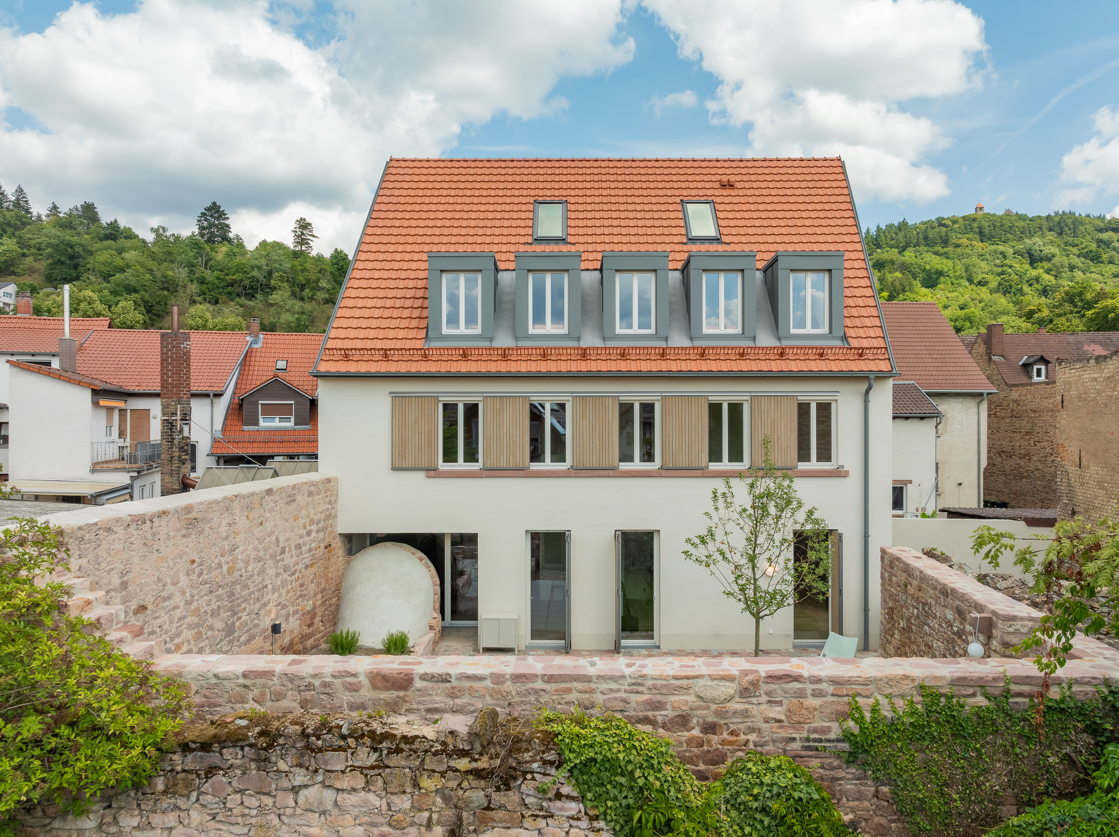 Neubau eines modernen Mehrfamilienhauses mit begrüntem Innenhof im historischen Kontext mit Besenstrichputz, Holzschalung, Schiebeläden und modernen Gauben.