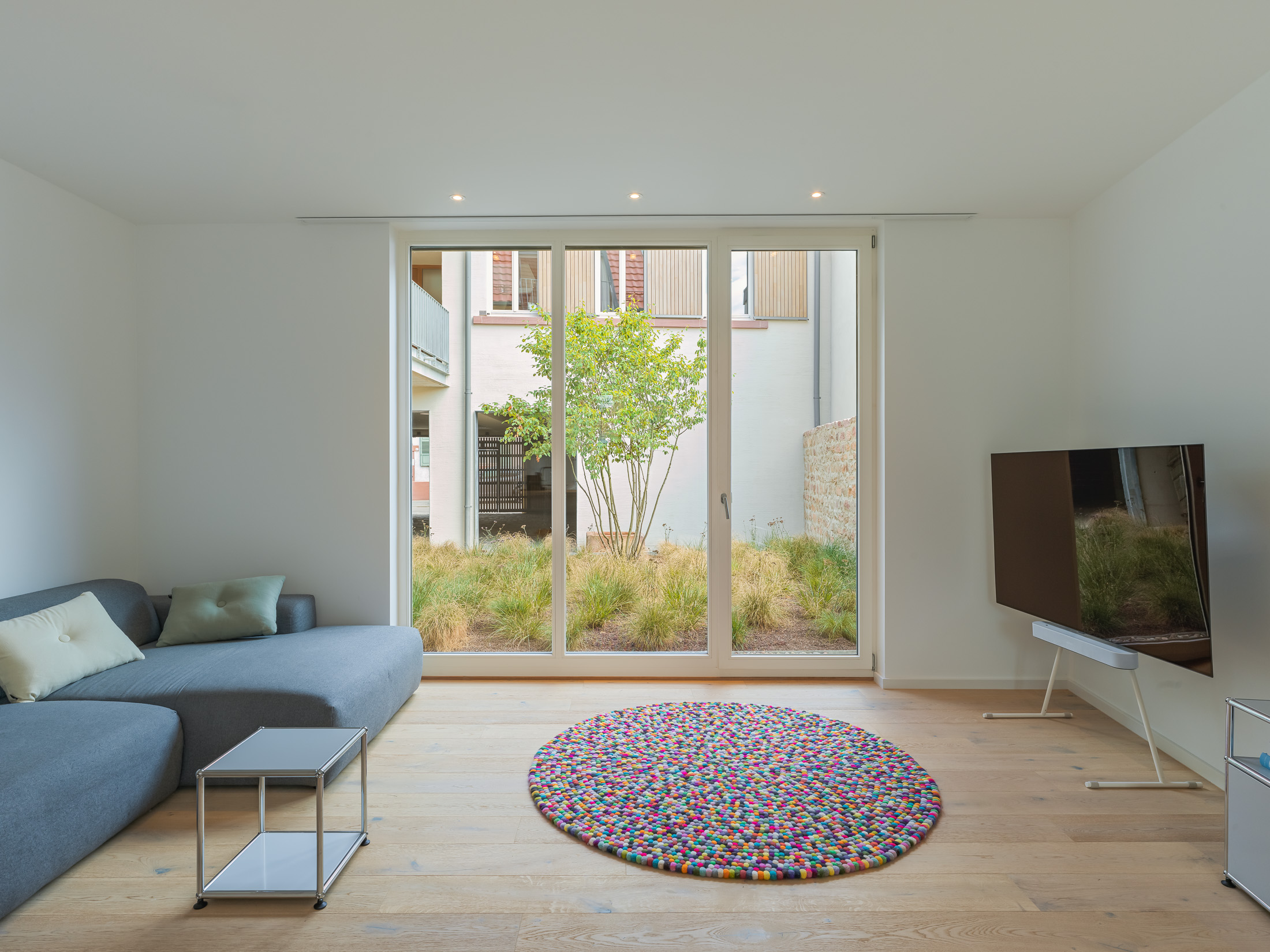 Ausblick Wohnbereich eines modernen Mehrfamilienhauses auf den begrünten gemeinschaftlichen Innenhof im historischen Kontext.