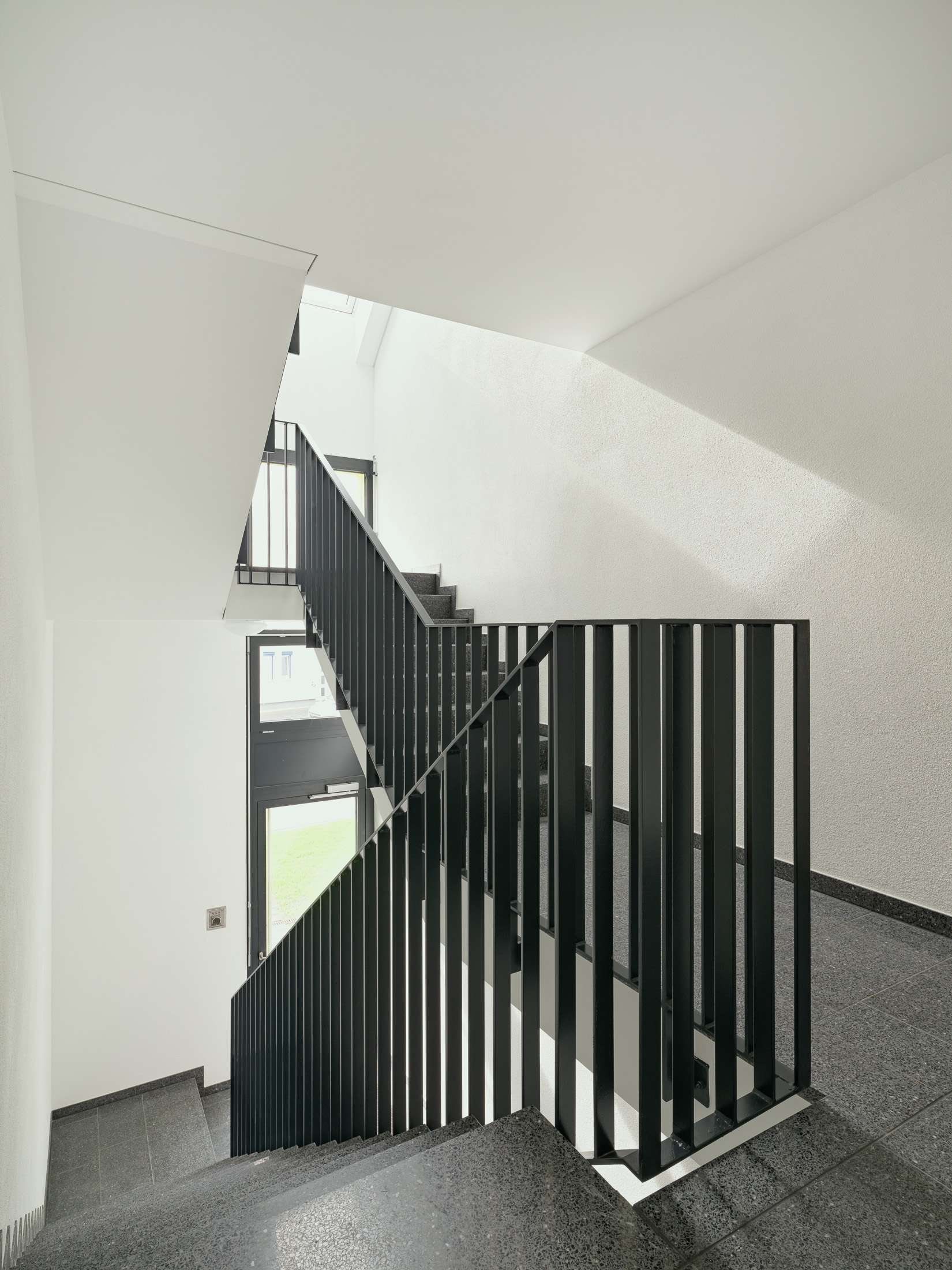 Mehrfamilienhausanlage für die VOLKSWOHNUNG GmbH in Karlsruhe-Durlach mit zweigeschossigen Hausgruppen und prägnanten Satteldächern, die sich um zwei begrünte, geschützte Innenhöfe organisieren; großzügige Verglasungen, Loggien und Dachgauben sowie eine flächenbündig integrierte Indach-Photovoltaikanlage prägen das architektonische Erscheinungsbild.