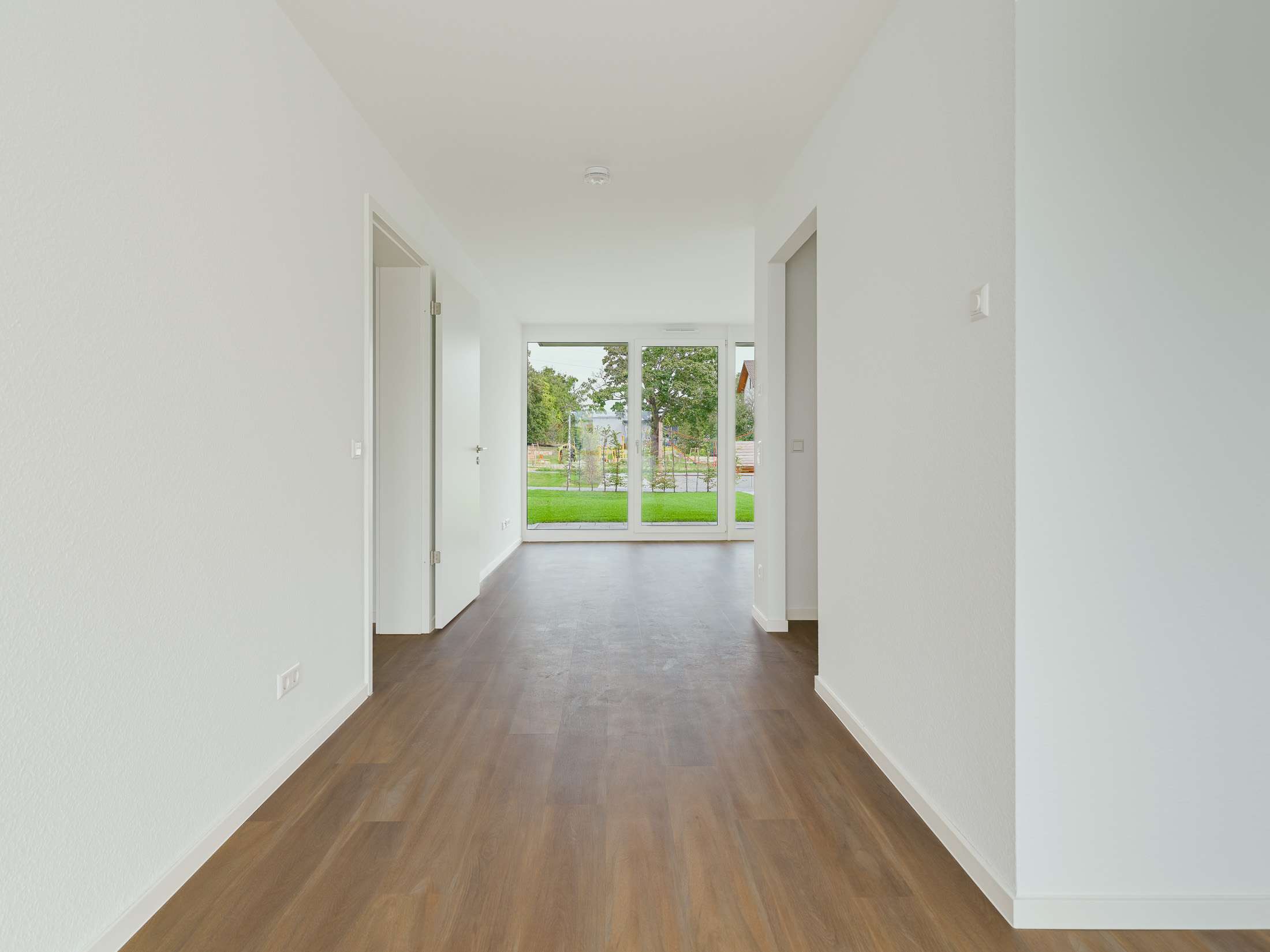 Mehrfamilienhausanlage für die VOLKSWOHNUNG GmbH in Karlsruhe-Durlach mit zweigeschossigen Hausgruppen und prägnanten Satteldächern, die sich um zwei begrünte, geschützte Innenhöfe organisieren; großzügige Verglasungen, Loggien und Dachgauben sowie eine flächenbündig integrierte Indach-Photovoltaikanlage prägen das architektonische Erscheinungsbild.