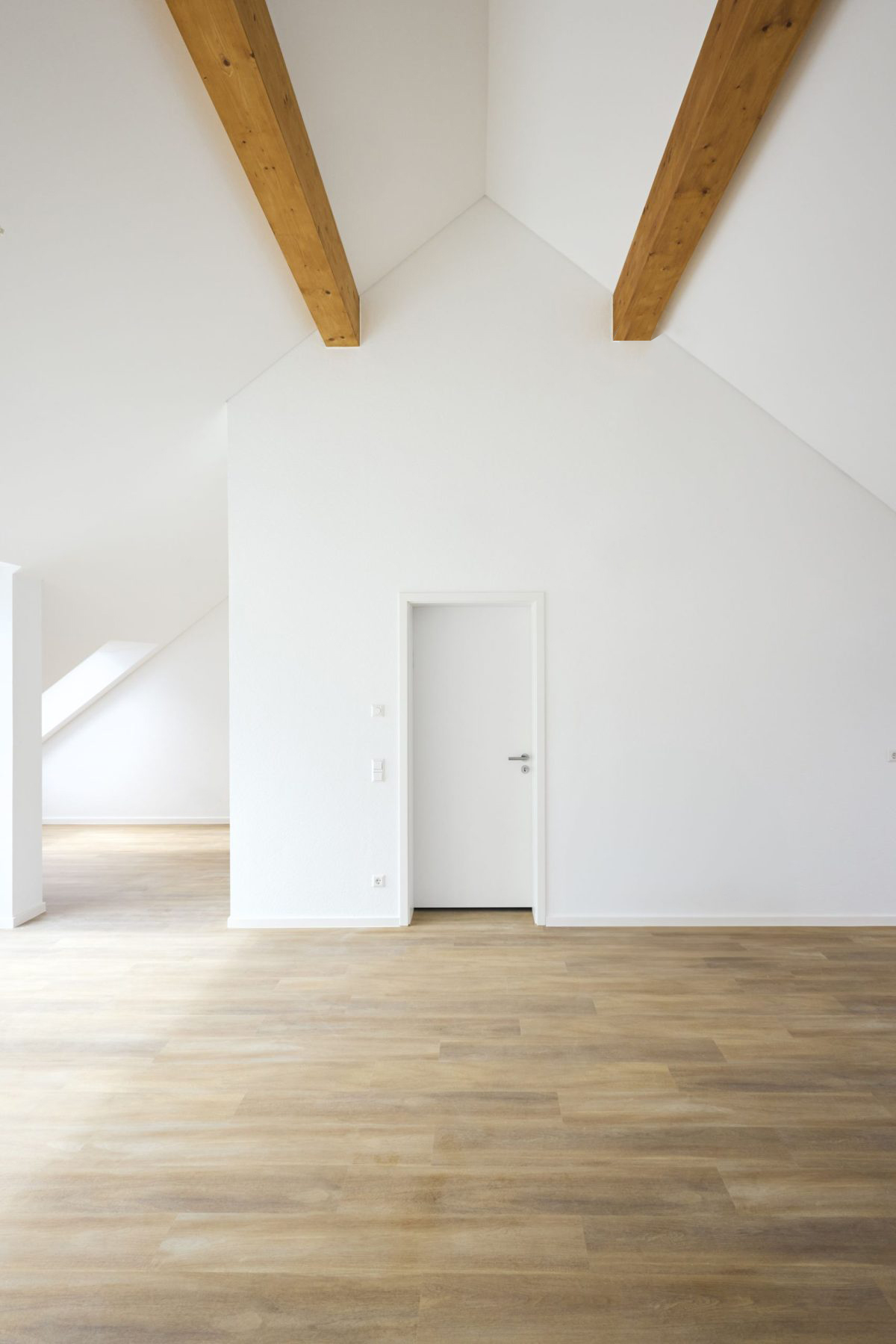 Mehrfamilienhausanlage für die VOLKSWOHNUNG GmbH in Karlsruhe-Durlach mit zweigeschossigen Hausgruppen und prägnanten Satteldächern, die sich um zwei begrünte, geschützte Innenhöfe organisieren; großzügige Verglasungen, Loggien und Dachgauben sowie eine flächenbündig integrierte Indach-Photovoltaikanlage prägen das architektonische Erscheinungsbild.