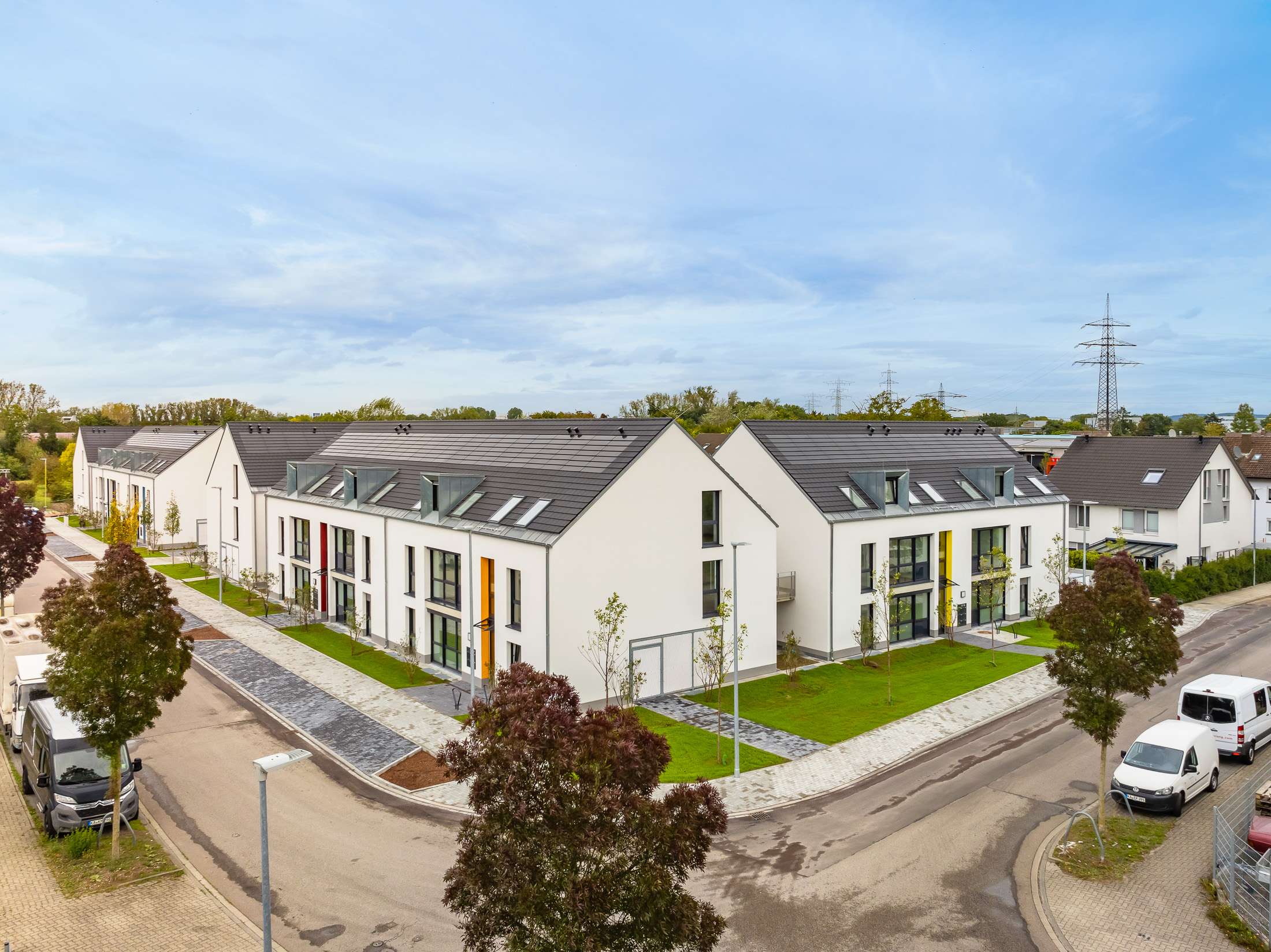 Mehrfamilienhausanlage für die VOLKSWOHNUNG GmbH in Karlsruhe-Durlach mit zweigeschossigen Hausgruppen und prägnanten Satteldächern, die sich um zwei begrünte, geschützte Innenhöfe organisieren; großzügige Verglasungen, Loggien und Dachgauben sowie eine flächenbündig integrierte Indach-Photovoltaikanlage prägen das architektonische Erscheinungsbild.