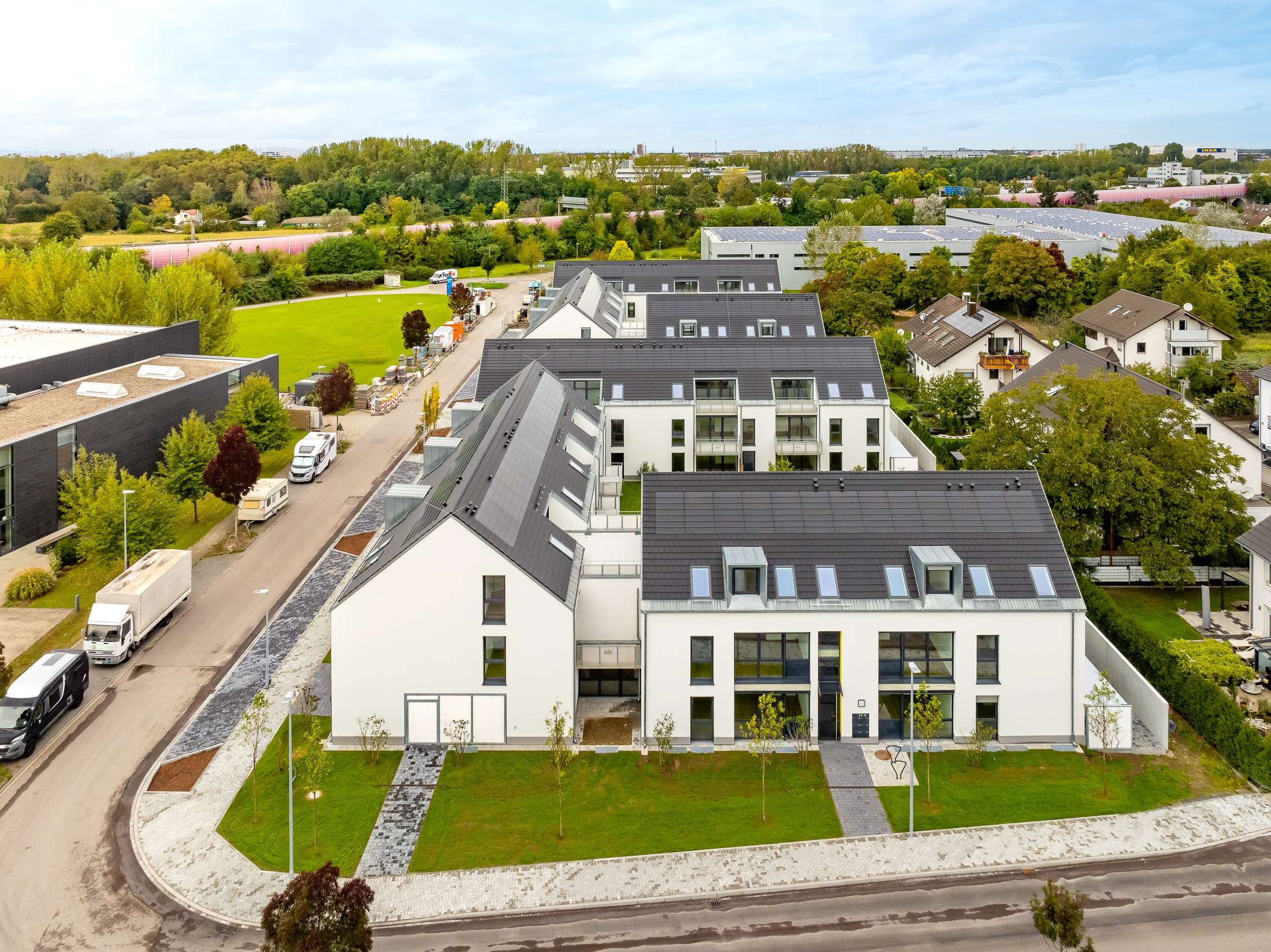 Mehrfamilienhausanlage für die VOLKSWOHNUNG GmbH in Karlsruhe-Durlach mit zweigeschossigen Hausgruppen und prägnanten Satteldächern, die sich um zwei begrünte, geschützte Innenhöfe organisieren; großzügige Verglasungen, Loggien und Dachgauben sowie eine flächenbündig integrierte Indach-Photovoltaikanlage prägen das architektonische Erscheinungsbild.