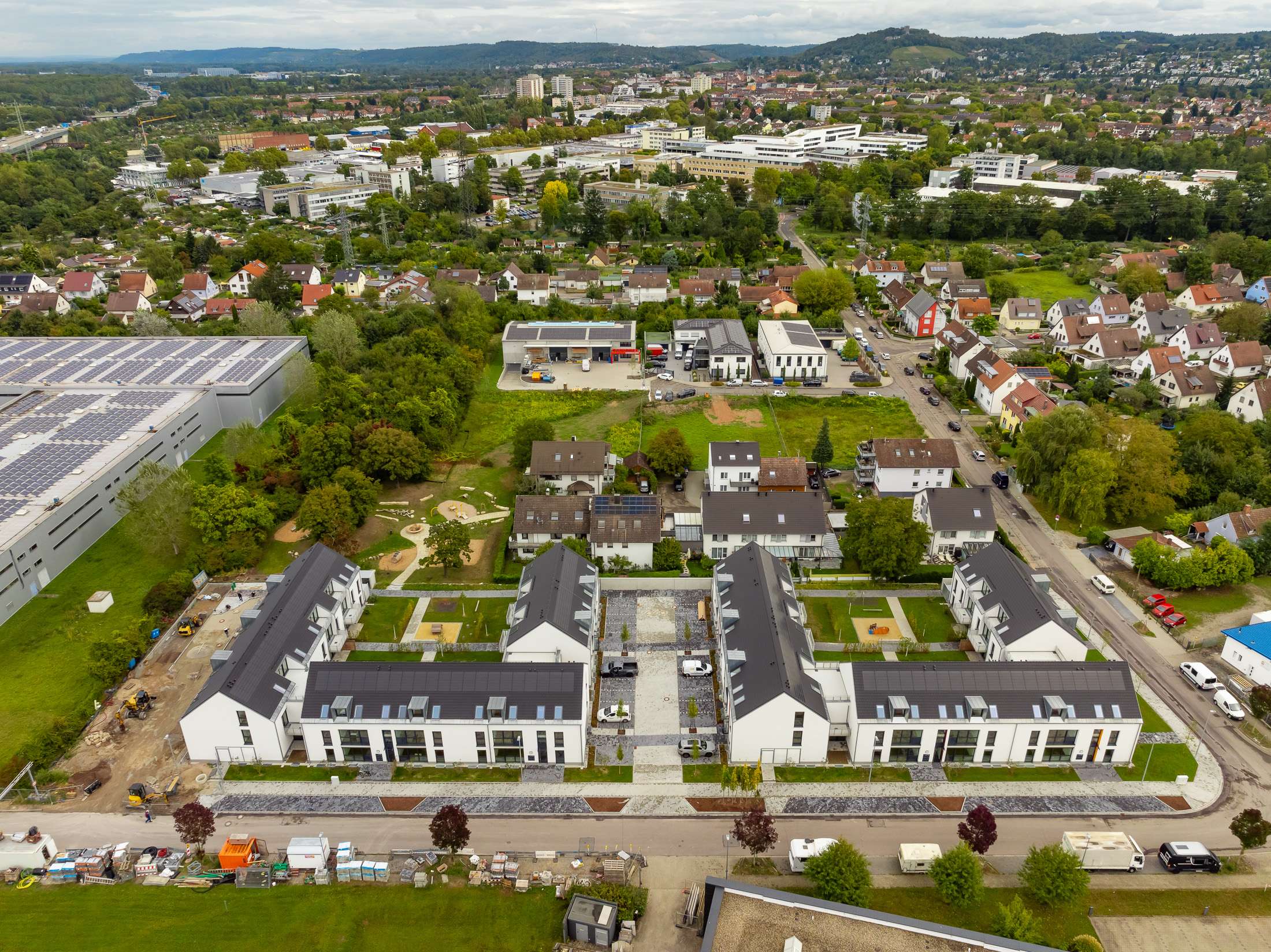 Mehrfamilienhausanlage für die VOLKSWOHNUNG GmbH in Karlsruhe-Durlach mit zweigeschossigen Hausgruppen und prägnanten Satteldächern, die sich um zwei begrünte, geschützte Innenhöfe organisieren; großzügige Verglasungen, Loggien und Dachgauben sowie eine flächenbündig integrierte Indach-Photovoltaikanlage prägen das architektonische Erscheinungsbild.