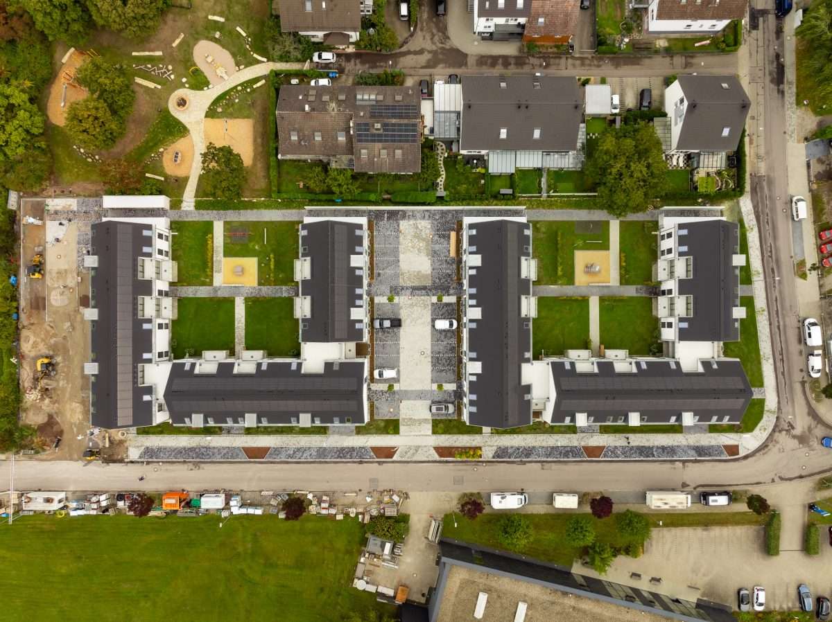 Mehrfamilienhausanlage für die VOLKSWOHNUNG GmbH in Karlsruhe-Durlach mit zweigeschossigen Hausgruppen und prägnanten Satteldächern, die sich um zwei begrünte, geschützte Innenhöfe organisieren; großzügige Verglasungen, Loggien und Dachgauben sowie eine flächenbündig integrierte Indach-Photovoltaikanlage prägen das architektonische Erscheinungsbild.