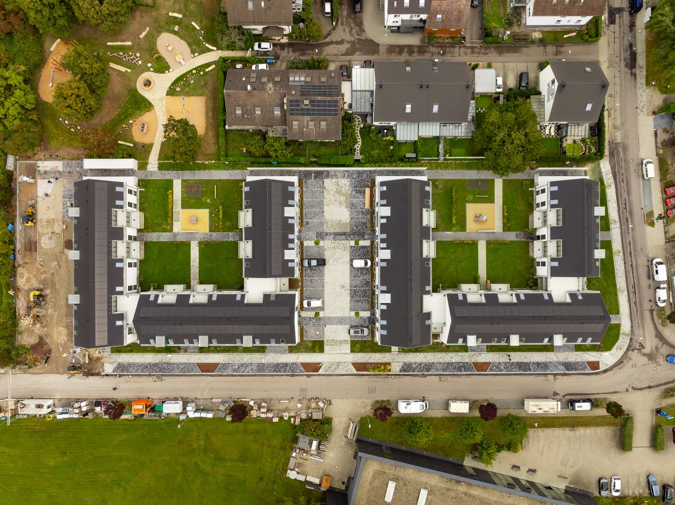 Mehrfamilienhausanlage für die VOLKSWOHNUNG GmbH in Karlsruhe-Durlach mit zweigeschossigen Hausgruppen und prägnanten Satteldächern, die sich um zwei begrünte, geschützte Innenhöfe organisieren; großzügige Verglasungen, Loggien und Dachgauben sowie eine flächenbündig integrierte Indach-Photovoltaikanlage prägen das architektonische Erscheinungsbild.