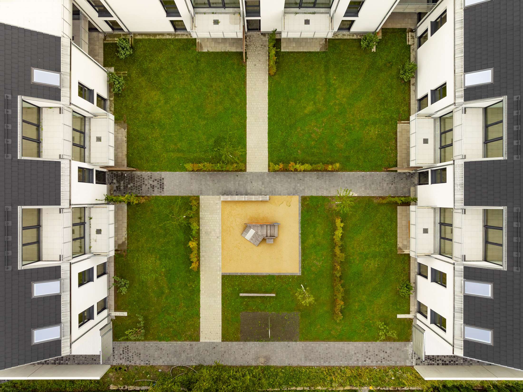 Mehrfamilienhausanlage für die VOLKSWOHNUNG GmbH in Karlsruhe-Durlach mit zweigeschossigen Hausgruppen und prägnanten Satteldächern, die sich um zwei begrünte, geschützte Innenhöfe organisieren; großzügige Verglasungen, Loggien und Dachgauben sowie eine flächenbündig integrierte Indach-Photovoltaikanlage prägen das architektonische Erscheinungsbild.