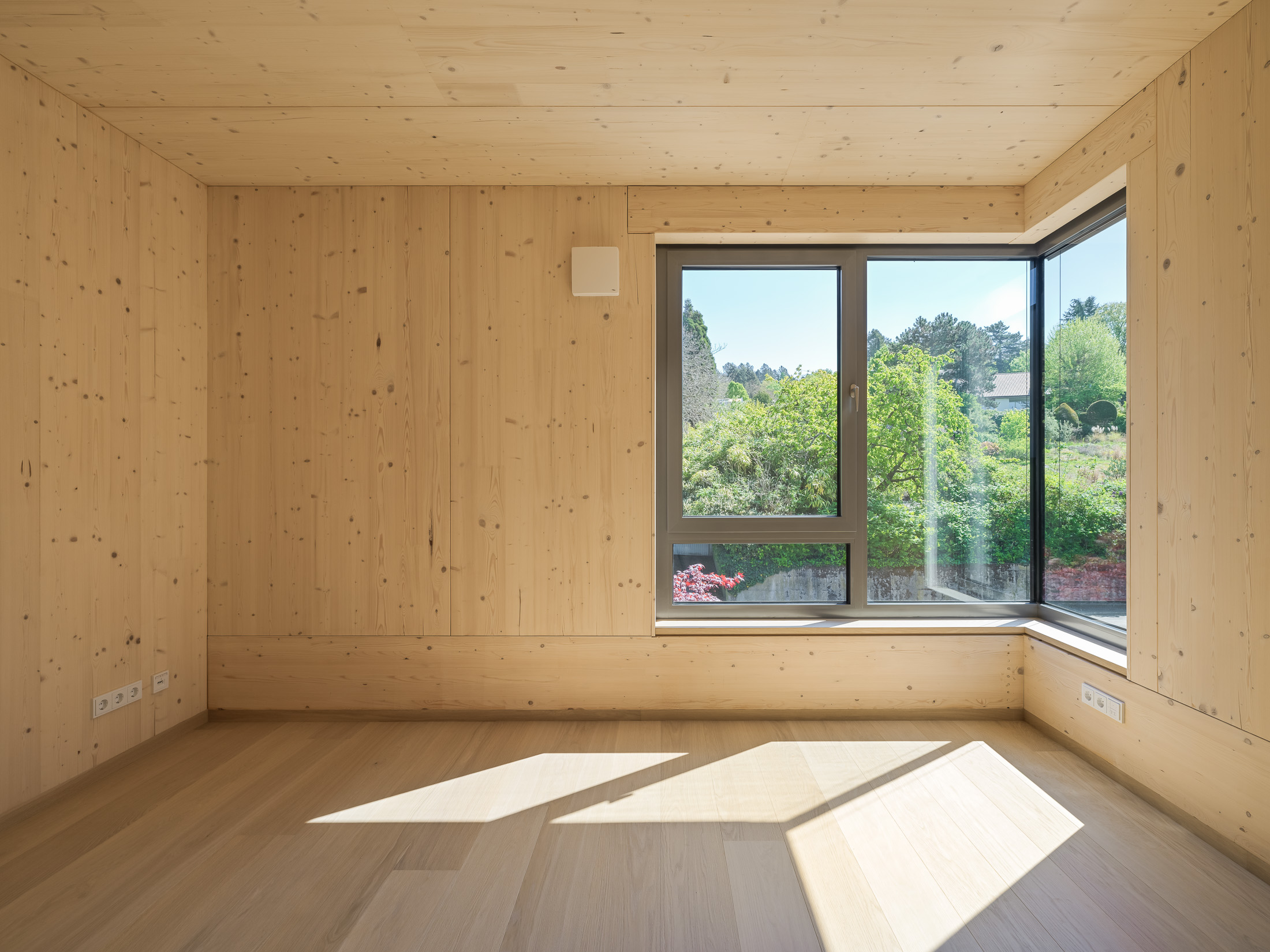 Architekturprojekt „Weiterbauen“ in Weinheim von Weber und Partner Architekten: Gesamtansicht der nachverdichteten Unternehmervilla aus den 1950er Jahren im parkartigen Hanggrundstück. Der gekürzte Bestandsbau mit hellen Klinkern und Holzaufstockung verbindet sich durch den Sandsteinsockel mit dem modernen Erweiterungsbau aus Massivholz.