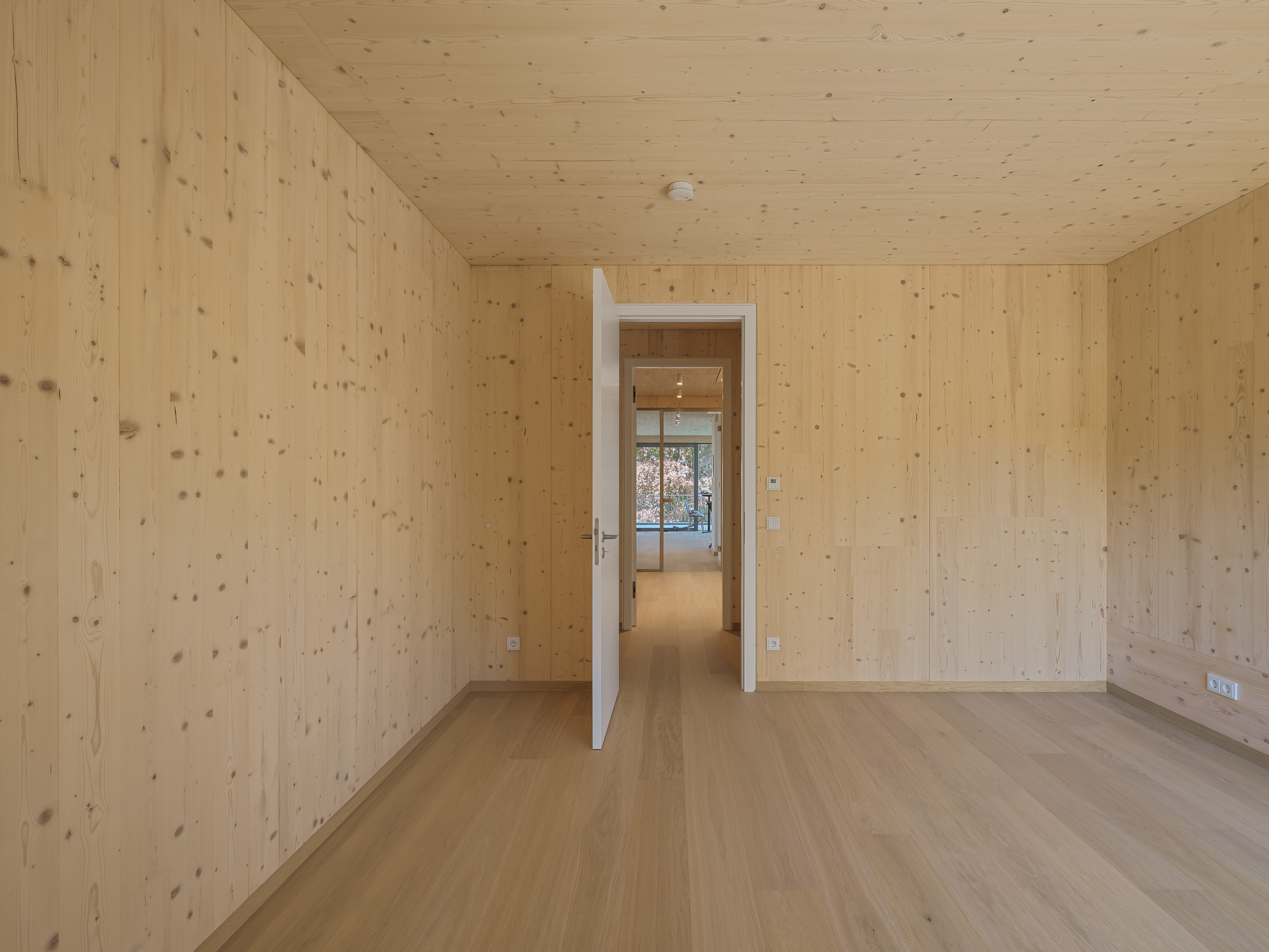 Architekturprojekt „Weiterbauen“ in Weinheim von Weber und Partner Architekten: Gesamtansicht der nachverdichteten Unternehmervilla aus den 1950er Jahren im parkartigen Hanggrundstück. Der gekürzte Bestandsbau mit hellen Klinkern und Holzaufstockung verbindet sich durch den Sandsteinsockel mit dem modernen Erweiterungsbau aus Massivholz.