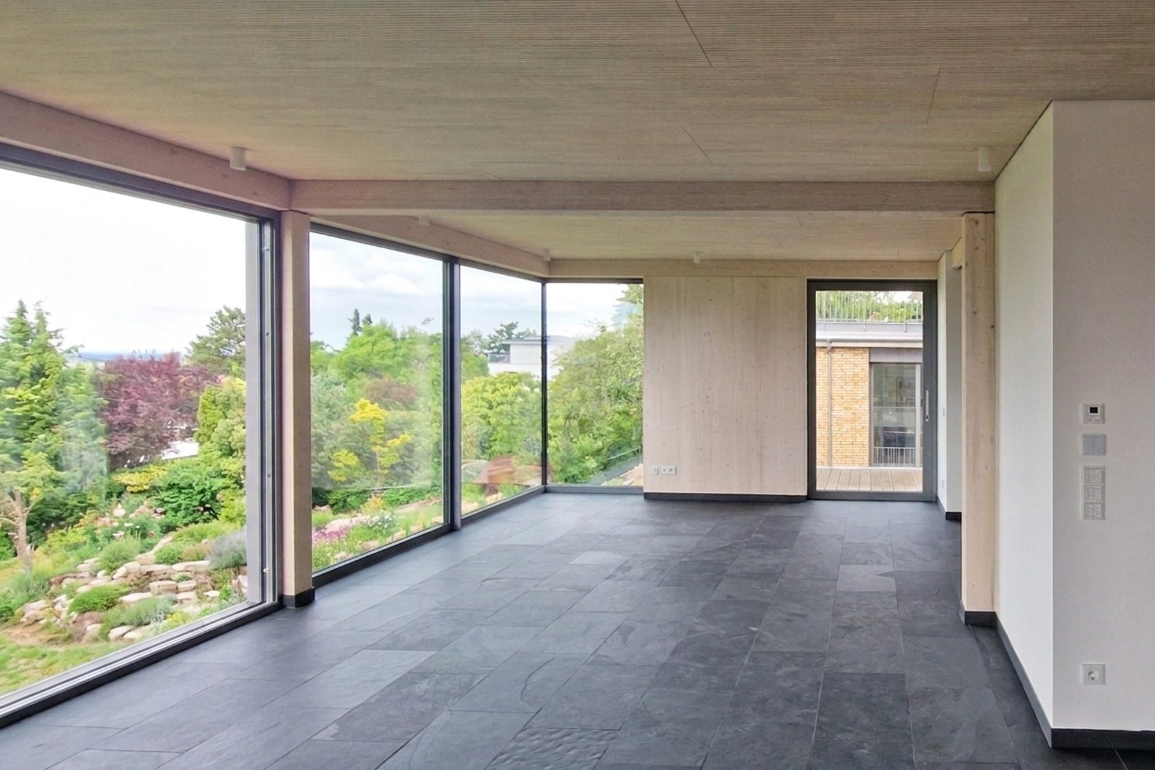Architekturprojekt „Weiterbauen“ in Weinheim von Weber und Partner Architekten: Gesamtansicht der nachverdichteten Unternehmervilla aus den 1950er Jahren im parkartigen Hanggrundstück. Der gekürzte Bestandsbau mit hellen Klinkern und Holzaufstockung verbindet sich durch den Sandsteinsockel mit dem modernen Erweiterungsbau aus Massivholz.