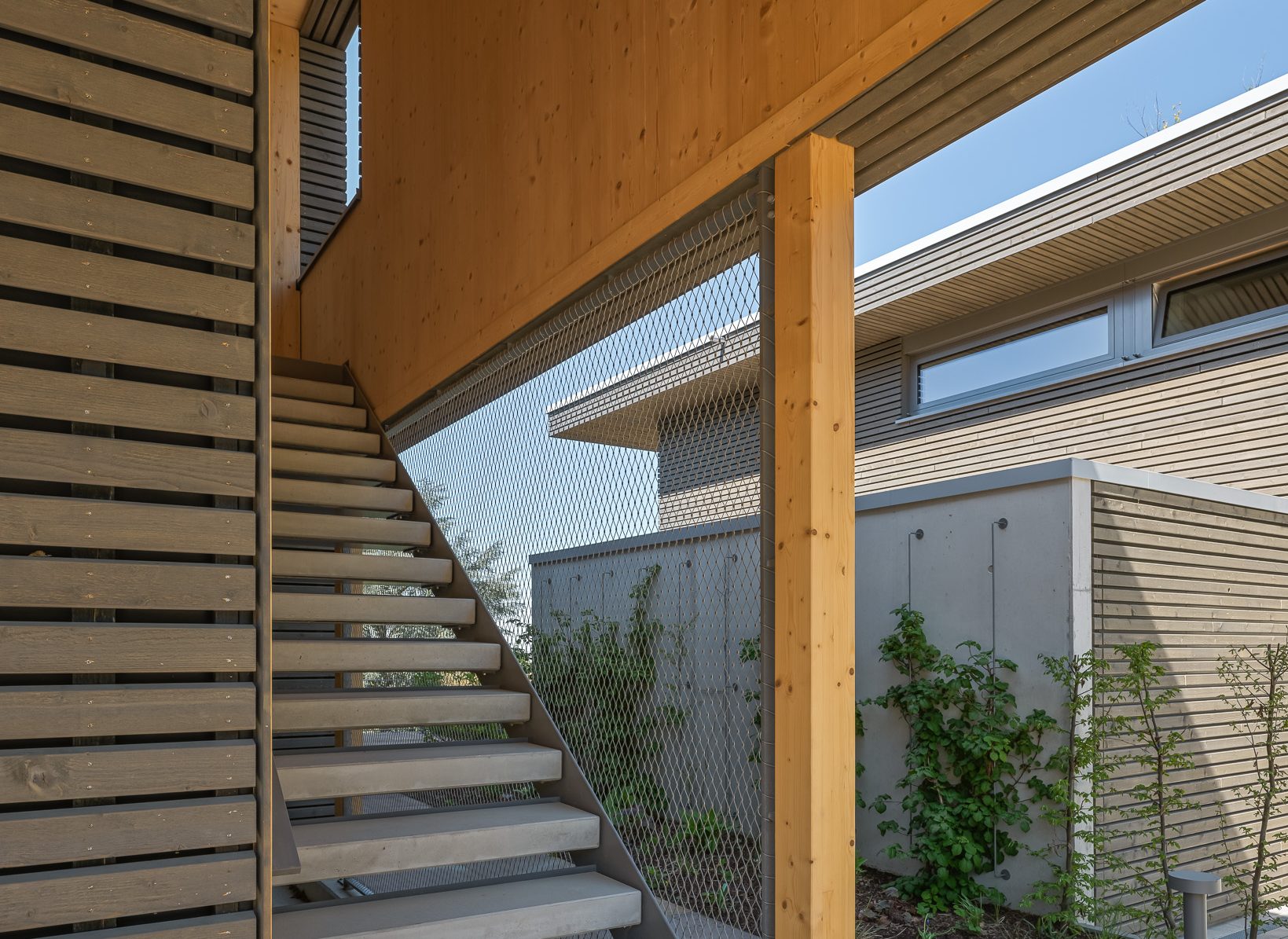 Architekturprojekt „Weiterbauen“ in Weinheim von Weber und Partner Architekten: Gesamtansicht der nachverdichteten Unternehmervilla aus den 1950er Jahren im parkartigen Hanggrundstück. Der gekürzte Bestandsbau mit hellen Klinkern und Holzaufstockung verbindet sich durch den Sandsteinsockel mit dem modernen Erweiterungsbau aus Massivholz.