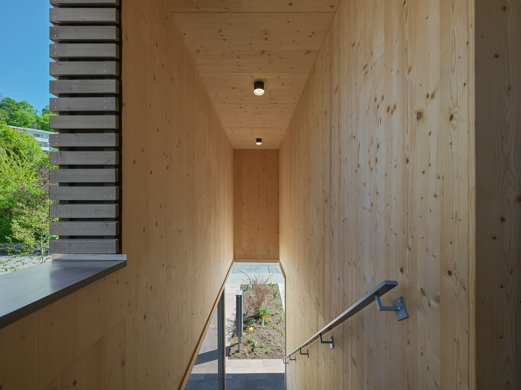Architekturprojekt „Weiterbauen“ in Weinheim von Weber und Partner Architekten: Gesamtansicht der nachverdichteten Unternehmervilla aus den 1950er Jahren im parkartigen Hanggrundstück. Der gekürzte Bestandsbau mit hellen Klinkern und Holzaufstockung verbindet sich durch den Sandsteinsockel mit dem modernen Erweiterungsbau aus Massivholz.